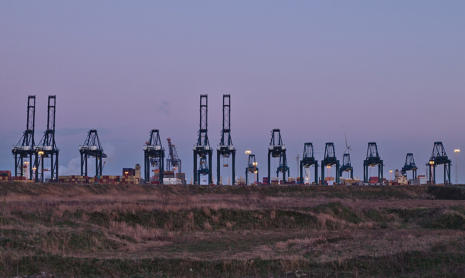 Container cranes at a port terminal at dusk, illustrating global trade